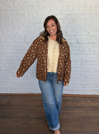 Woman wearing a brown floral jacket with a taupe top denim jeans and brown shoes.