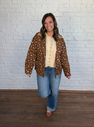 Woman wearing a brown floral jacket with a taupe top denim jeans and brown shoes.