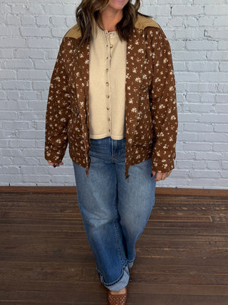 Woman wearing a brown floral jacket with a taupe top denim jeans and brown shoes.
