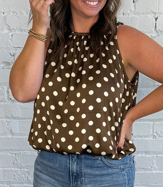Women wearing a brown and cream polka dot bubble top with cuffed jeans and boots.