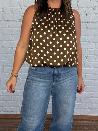 Women wearing a brown and cream polka dot bubble top with cuffed jeans and boots.