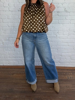 Women wearing a brown and cream polka dot bubble top with cuffed jeans and boots.