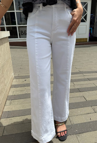 Person wearing white pants standing on a sidewalk.
